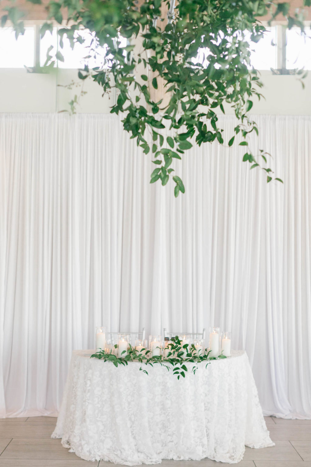 Elegant Romantic Wedding Reception Decor, Sweetheart Table with Delicate White Lace Linens, Greenery and Candles, Linen Drapery Backdrop, Greenery Chandelier | Tampa Wedding Florist Bruce Wayne Florals | Wedding Planner Parties A'la Carte | Wedding Linen Drapery Rental Gabro Event Services