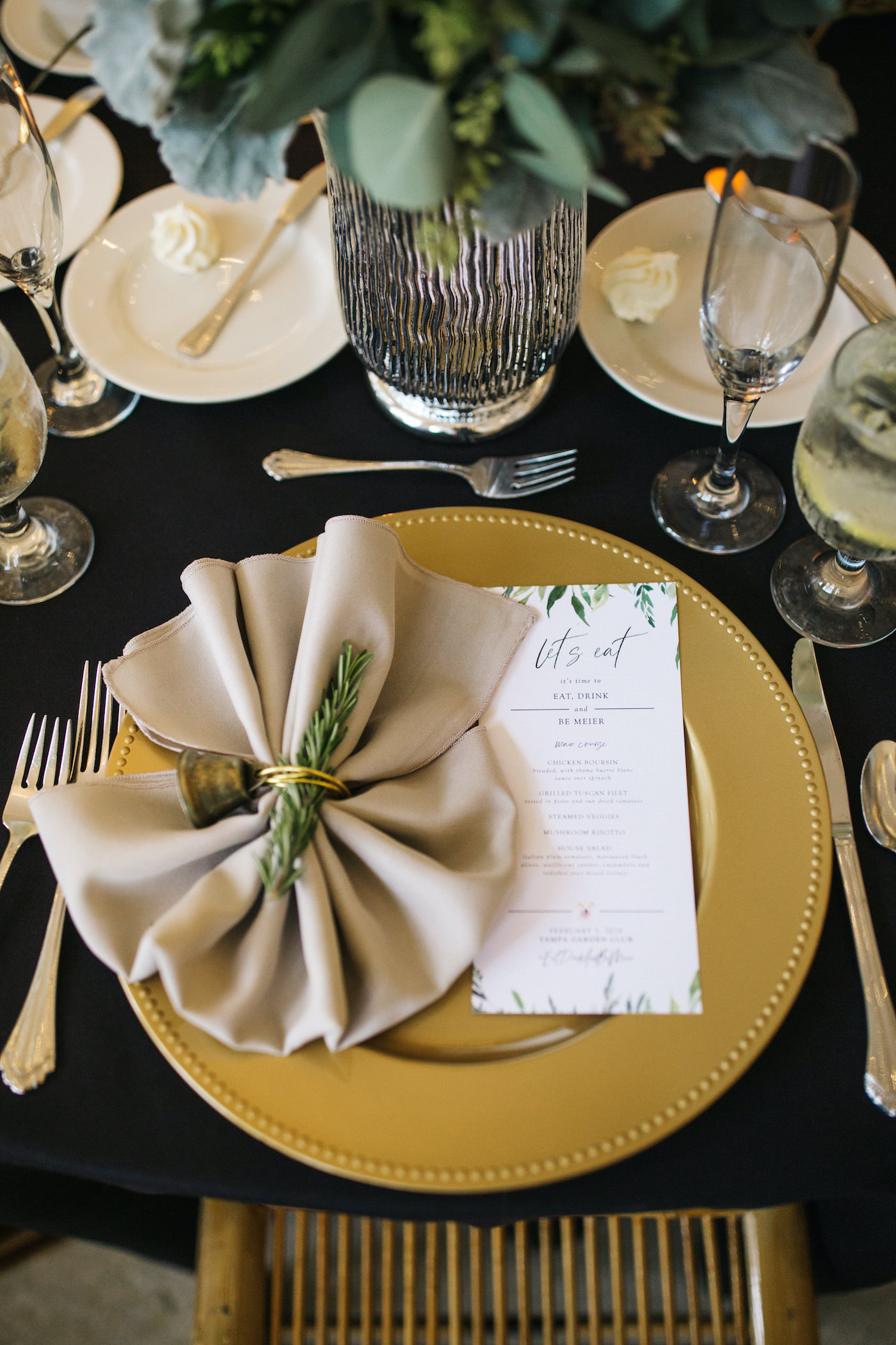 Black and White and Gold Wedding Place Setting with Black Table Linen and Gold Charger Plate and Taupe Napkin Fan accented with Fresh Rosemary Herb Sprig and Wedding Menu Card | Winsor Event Studio