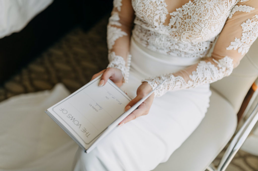 Classic Wedding Details, Florida Bride Reading Vow Book Florida Wearing Lace and Illusion Lace Long Sleeve Wedding Dress