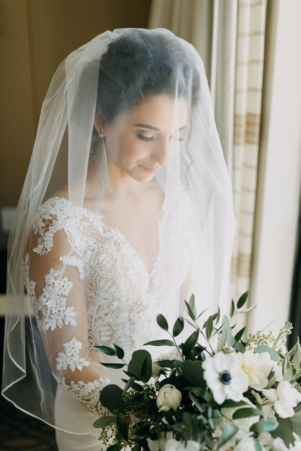 Classic Tampa Bay Bridal Portrait, Bride with Veil in Timeless White Illusion Lace Long Sleeve Martina Liana Wedding Dress Holding Classic White Floral Bouquet with Greenery | Tampa Bay Wedding Hair and Makeup Artist Femme Akoi Beauty Studio | Florida Wedding Venue The Hotel Zamora
