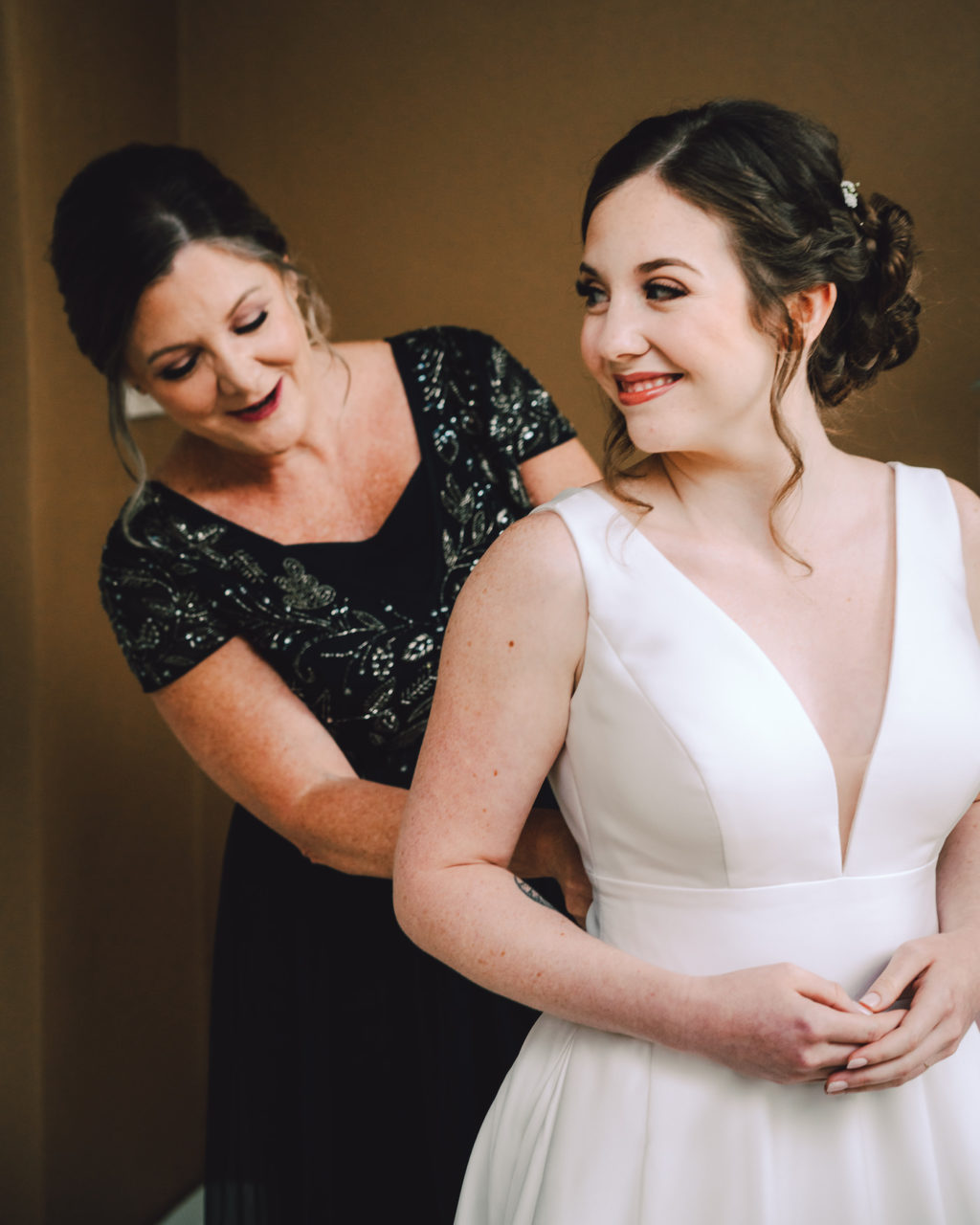 Mom Helping Bride Get Dressed and Ready | Stella York Satin V Neck Simple Classic Bridal Gown A Line Ballgown | Savannah Olivia Beauty Boutique