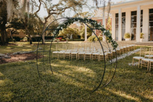 Tampa Wedding Venue The Tampa Garden Club Outdoor Lawn Reception overlooking Tampa Bay Bayshore Water View | Gold Chiavari Chairs and Ivory Rose Petals Aisle with Metal Round Moon Arch
