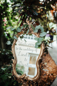 Antique Gold Mirror with White Script Font Wedding Ceremony Welcome Sign and Silver Dollar Eucalyptus
