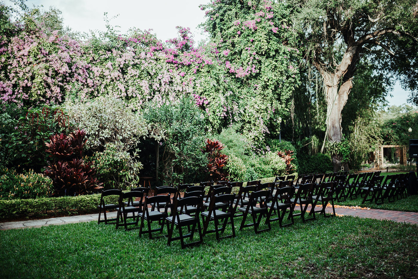 Outdoor Wedding Ceremony with Black Wooden Folding Chairs at St. Petersburg Wedding Venue Sunken Gardens | Tampa Wedding Planner Kelly Kennedy Weddings and Events