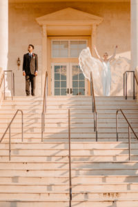 Bride and Groom Outdoor Wedding Portrait on Grand Staircase | Embroidered Floral Lace V Neck Bridal Gown and Groom in Classic Black Tux
