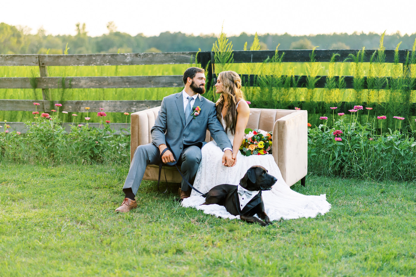 Bright Colorful Florida Citrus Wedding Inspiration | Bridal Bouquet with Pink Orange and Yellow Roses | Groom in Grey Suit with Grey Neck Tie | Wedding Dog of Honor with Bow Tie Collar | Outdoor Bride and Groom Portrait with Love Seat