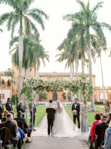 Romantic, Modern Florida Bride and Groom During Outdoor Wedding Ceremony with Jewish Altar, Ghost Chairs, Clear Acrylic Chuppah with Lush Ivory Floral Bouquets and Greenery Decor, In Courtyard of The Ringling Museum | Sarasota Wedding Planner NK Weddings