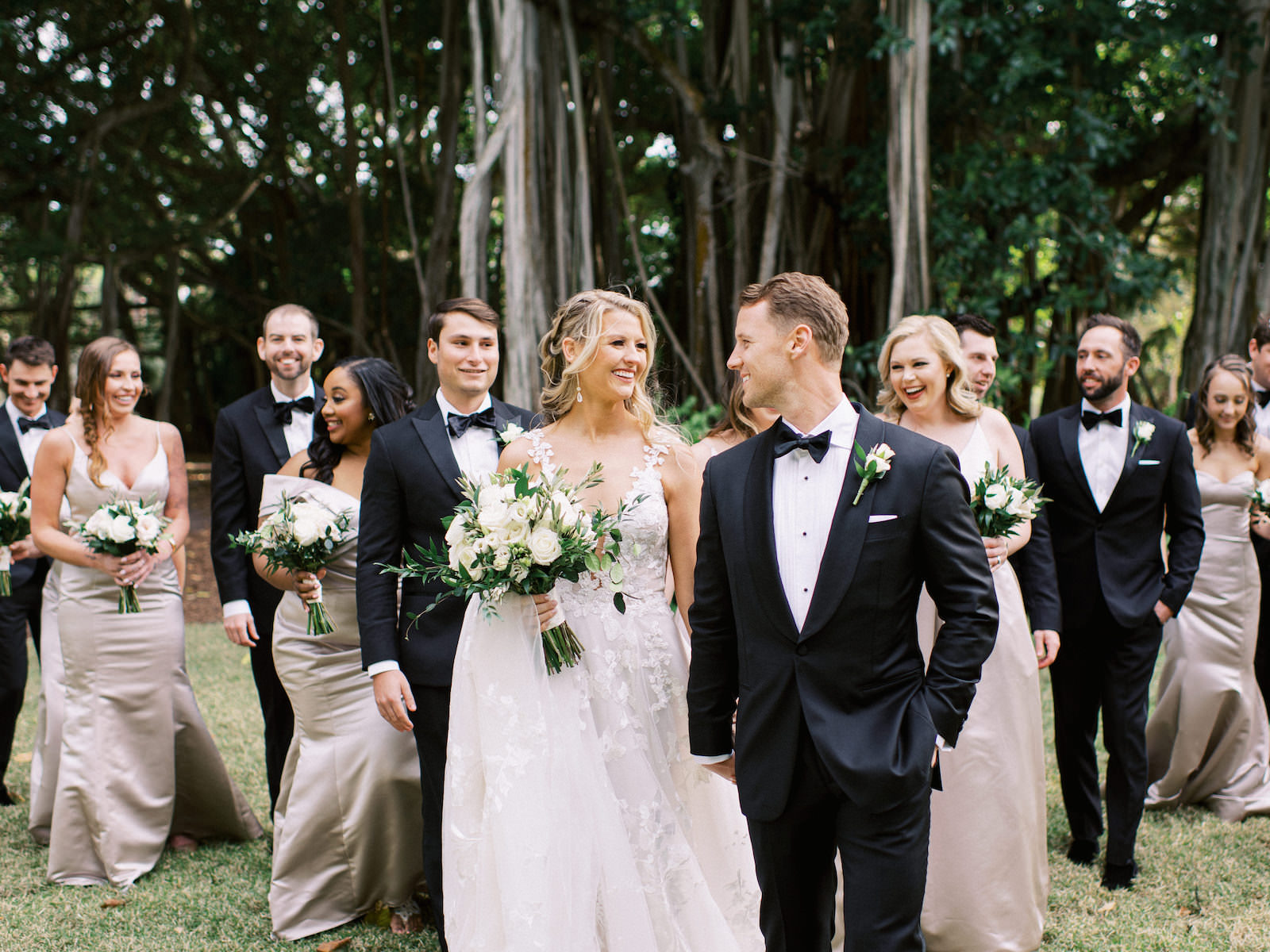 Modern Day Fairytale Florida Wedding Party, Bride Wearing Galia Lahav Wedding Dress Holding White Floral and Ivory Rose Bouquet with Greenery, Bridesmaids in Blush Satin Hayley Paige Occasions Long Mix and Match Dresses, Groomsmen in Classic Black Bowtie Tuxedo | Tampa Dress Shop Isabel O’Neil Bridal | Sarasota Hair and Makeup by Femme Akoi Beauty Studios | Sarasota Wedding Planner NK Weddings | Tampa Bay Bridesmaids Dress Shop Bella Bridesmaids Tampa