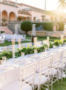 Romantic, Modern Outdoor Florida Wedding Reception, Wedding Party Long Feasting Table with White Linens and Clear Acrylic Chiavari Chairs, Greenery Garland Centerpiece with Tall Taper Candles, Glass Stemware and Chargers, Space Heaters, Black and White Checkered Dance Floor | Luxury Sarasota Wedding Planner NK Weddings