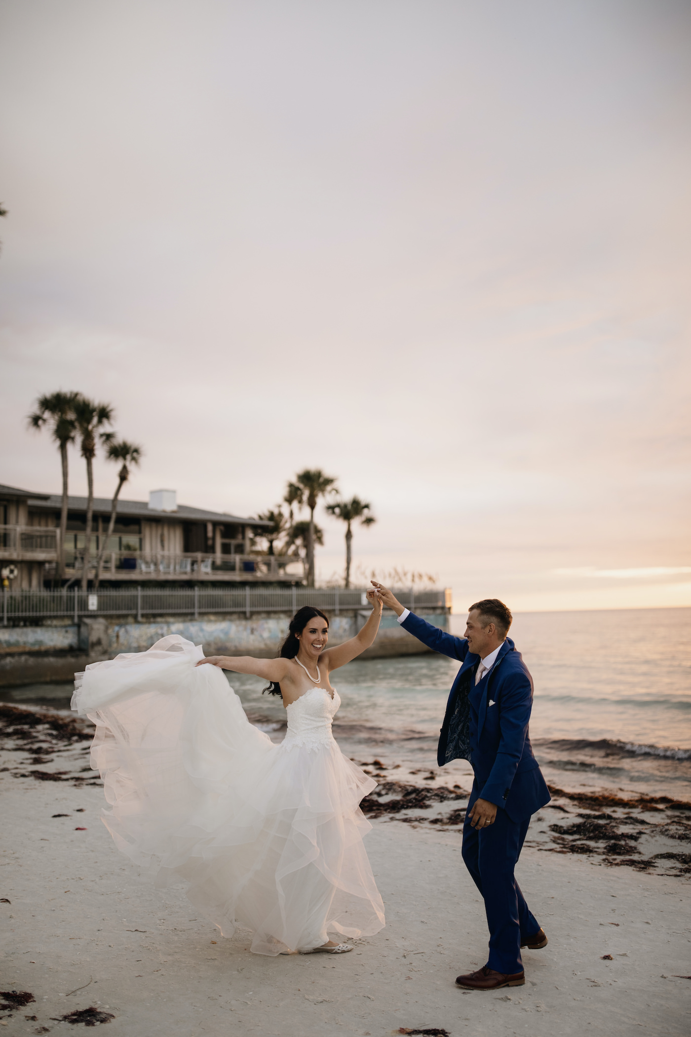 Bride and Groom Outdoor Portrait Sarasota Beach Wedding Ceremony on Siesta Key | Groom in Navy Blue Suit with Blush Pink Neck Tie | Horsehair Trim Tiered Organza Tulle Ballgown Bridal Gown with Sweetheart Neckline and Lace Bodice | Sarasota Wedding Dress Shop Truly Forever Bridal