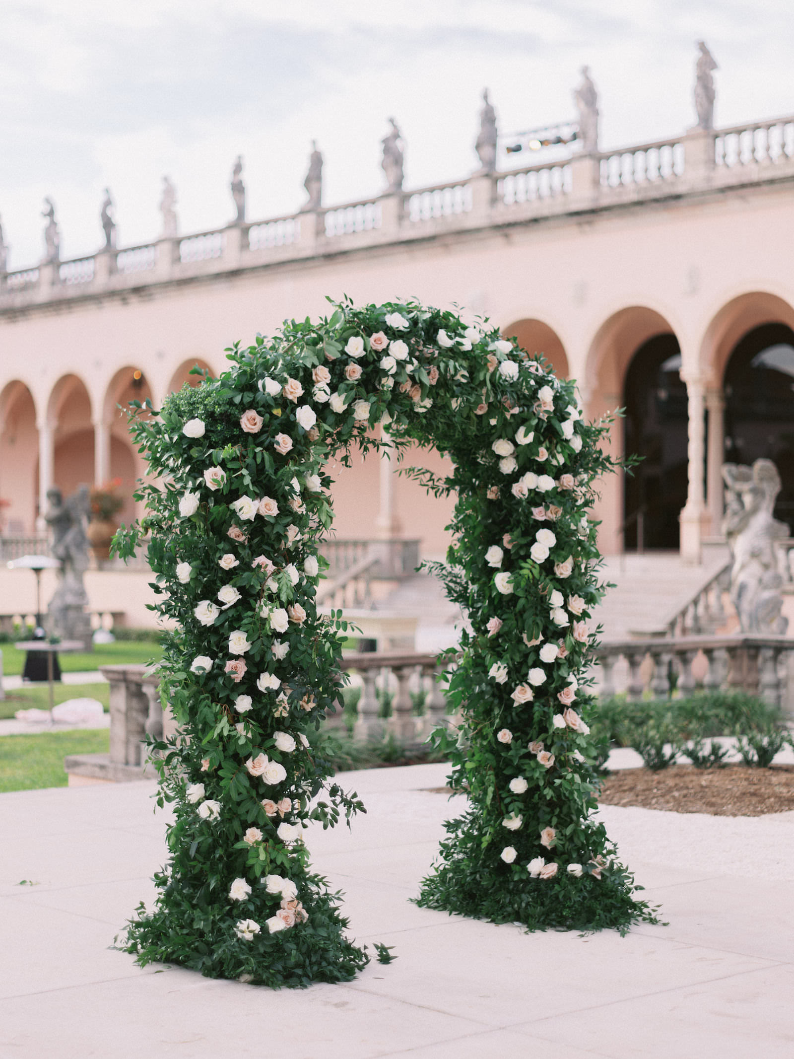 Fairytale Inspired Florida Wedding Ceremony at The Ringling Museum of Art Courtyard in Sarasota, Large Garden-Inspired Floral Arch with White and Blush Pink Roses | Florida Wedding Planner NK Weddings