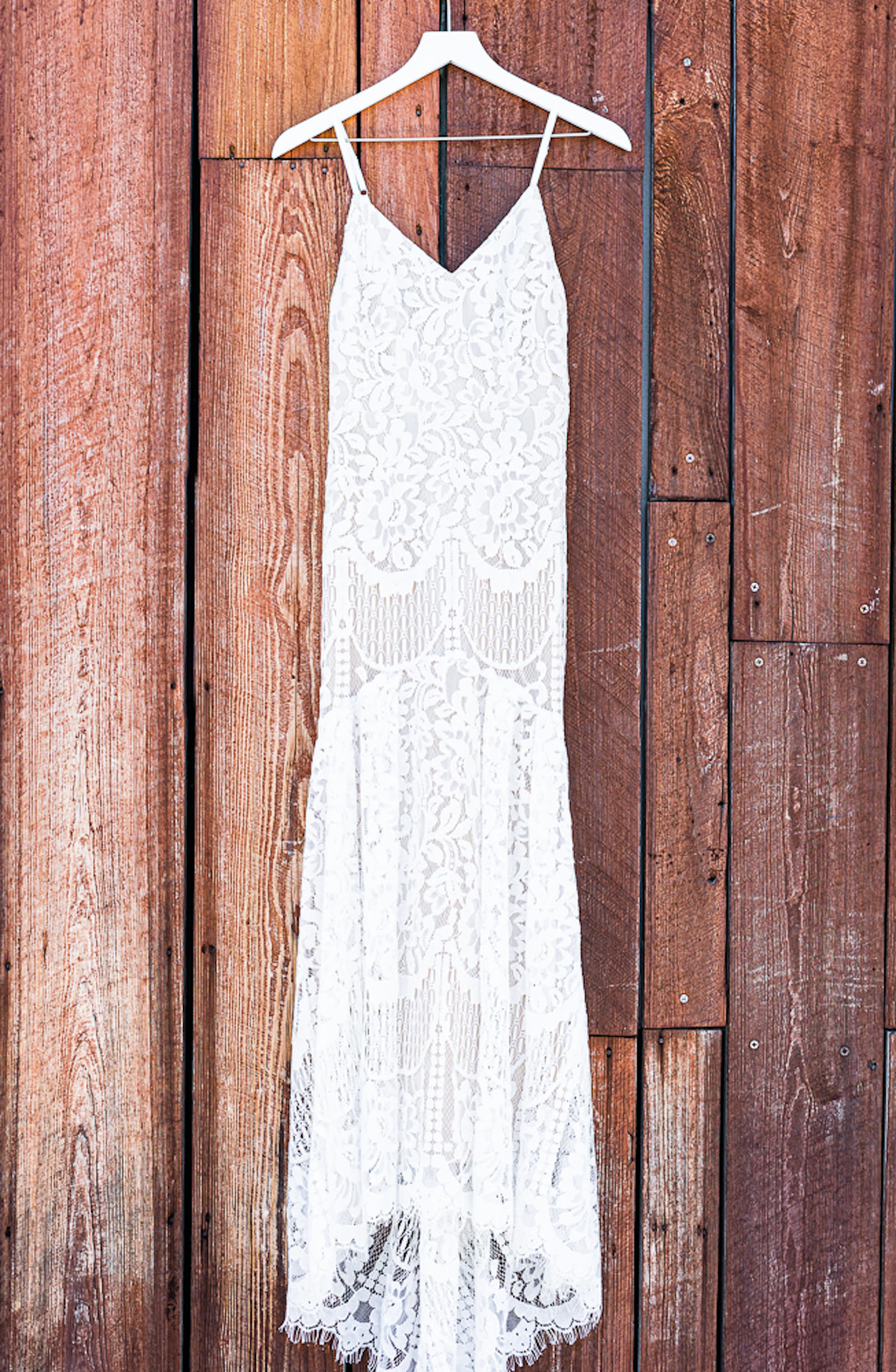 Lace Sheath Spaghetti Strap V Neck Boho Bridal Gown Wedding Dress | Wedding Dress Hanger Shot on Rustic Wood Wall