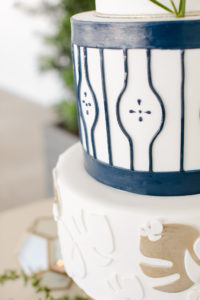 Clearwater Beach Wedding Venue Hilton Clearwater Beach | Modern Tropical Beach Outdoor Wedding Cake Table with Four Tier Gold and Navy Wedding Cake with Monstera Palm Leaf Motif | The Artistic Whisk