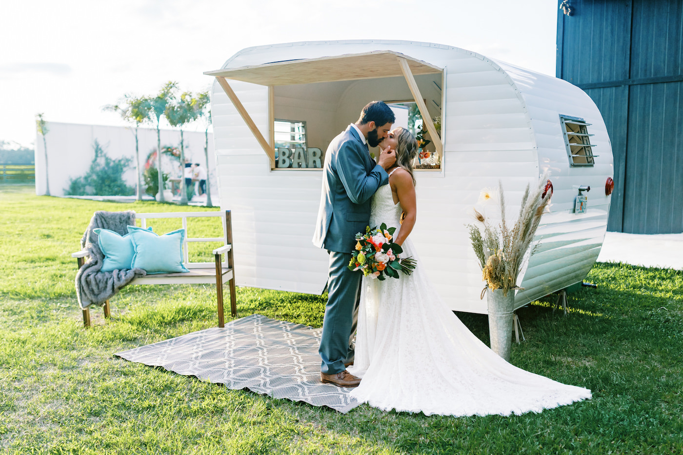 Bright Colorful Florida Citrus Wedding Inspiration | Bridal Bouquet with Pink Orange and Yellow Roses | Groom in Grey Suit with Grey Neck Tie | Outdoor Bride and Groom Portrait with Vintage Camper Mobile Bar Side Car