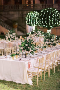 Modern Day Fairytale Wedding Outdoor Nighttime Reception and Decor, Long Head Party Feasting Table with Blush Pink Linens, Gold Chiavari Chairs, Lush Floral Centerpieces with Garden Inspired Decor, and Illuminating Lighting | Museum of Art Courtyard at The Ringling | Sarasota Wedding Planner NK Weddings