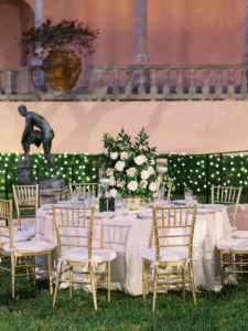 Modern Day Fairytale Wedding Outdoor Nighttime Reception and Decor, Round Table with Blush Pink Linens, Gold Chiavari Chairs, Lush Rose and Greenery Centerpieces with Garden Inspired Decor, and Illuminating Lighting | Museum of Art Courtyard at The Ringling | Sarasota Wedding Planner NK Weddings