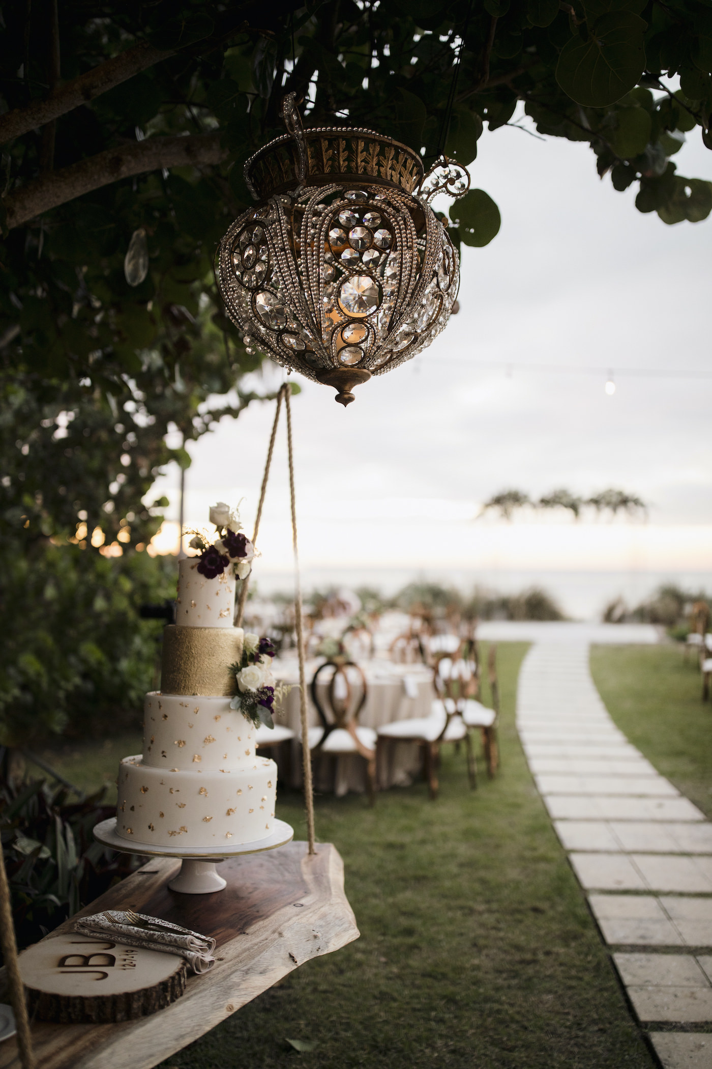 Suspended Floating Wedding Cake Display | Live Edge Wood Wedding Cake Table | Four Tier Ivory and Gold Fleck Wedding Cake with Fresh Flowers | Outdoor Sarasota Beach Wedding Reception