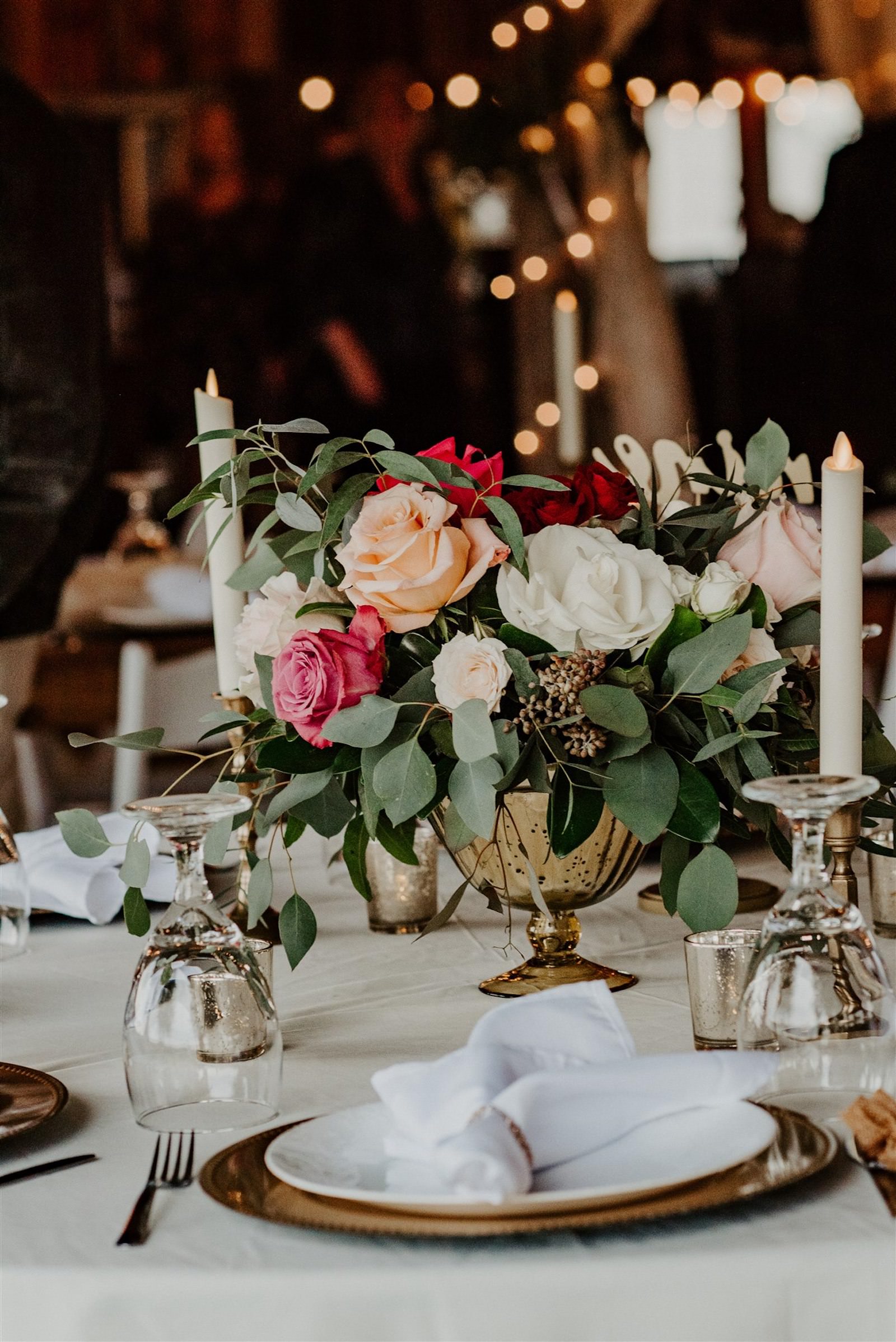 Rustic Barn Tampa Wedding Gold Compote Vase Centerpieces with Blush Pink and Deep Red Burgundy Roses and Eucalyptus Greenery | Reception Tables with Ivory Champagne Linens and Taper Candlestick Candles | Tampa Wedding Florist Monarch Events and Designs