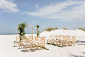 Clearwater Beach Wedding Venue Hilton Clearwater Beach | Modern Tropical Beach Wedding Ceremony with Gold Chiavari Chairs and Champagne Sash Bows and Tropical Palm Frond Leaf Floral Arrangements on Bamboo Arch | Palm Leaves Lining Beach Sand Aisle