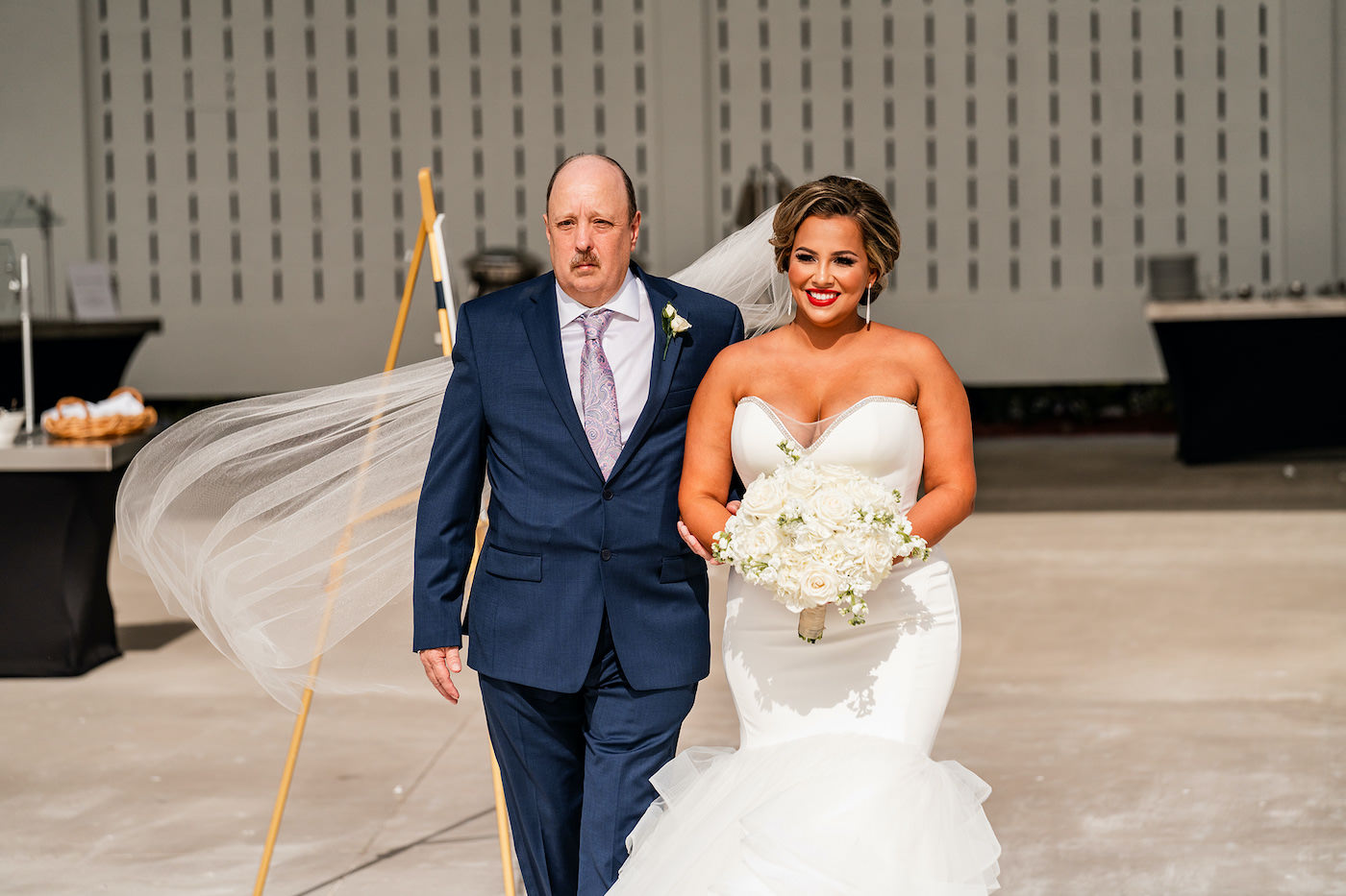 Romantic Clearwater Bride and Father Walk Down the Aisle in Outdoor Florida Wedding, Bride Wearing Romantic Fit and Flare White Dress, Holding Ivory Mixed Floral Bouquet with Roses and Greenery | Tampa Bay Hair and Makeup Artist Michele Renee The Studio