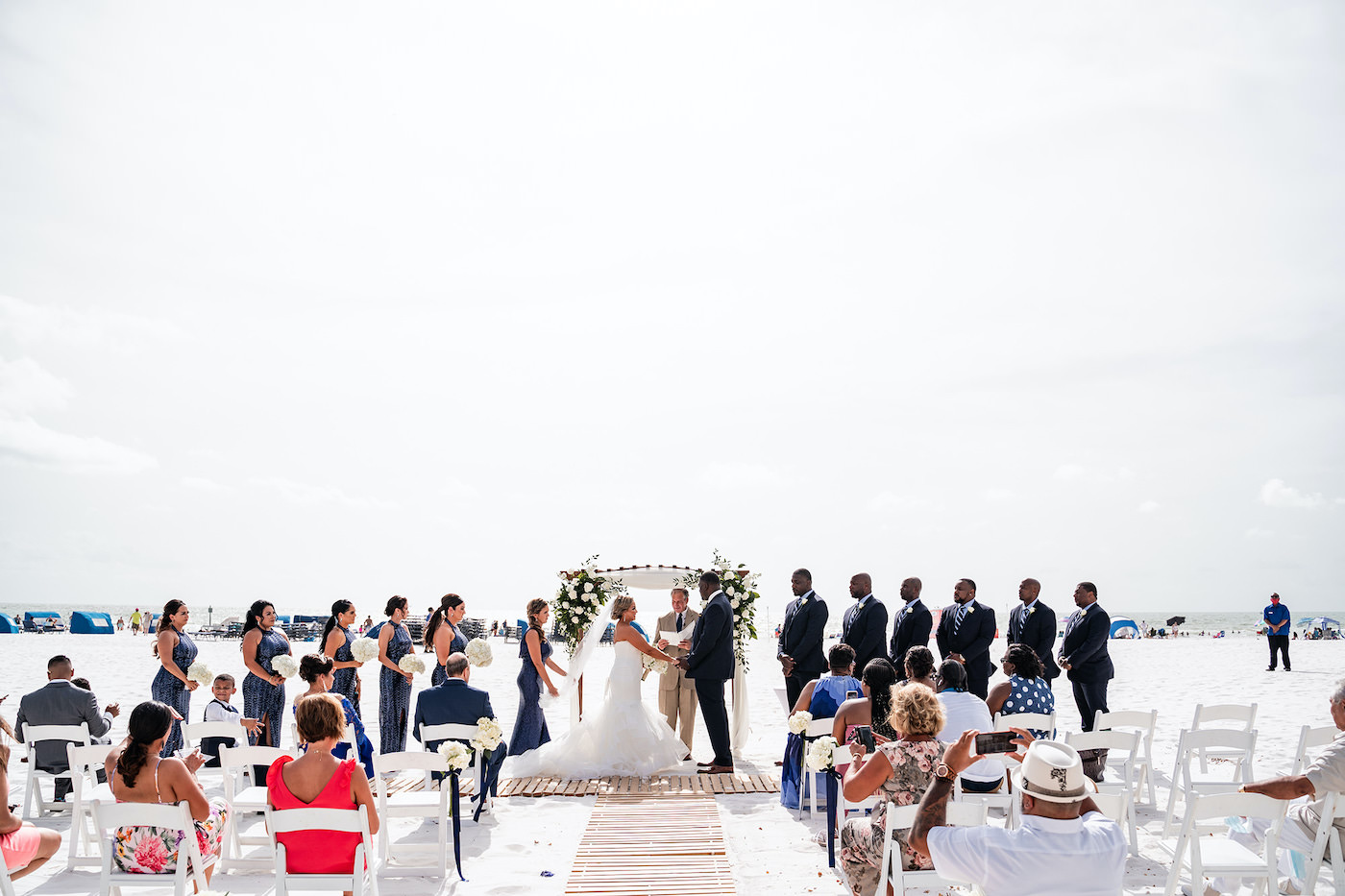 Florida Bride and Groom Exchange Vows in Outdoor Beachfront Ceremony, Tampa Bay Wedding Party with Romantic Tropical Ceremony Decor, White Roses and Greenery | Tampa Bay Hotel and Wedding Venue Hilton Clearwater Beach