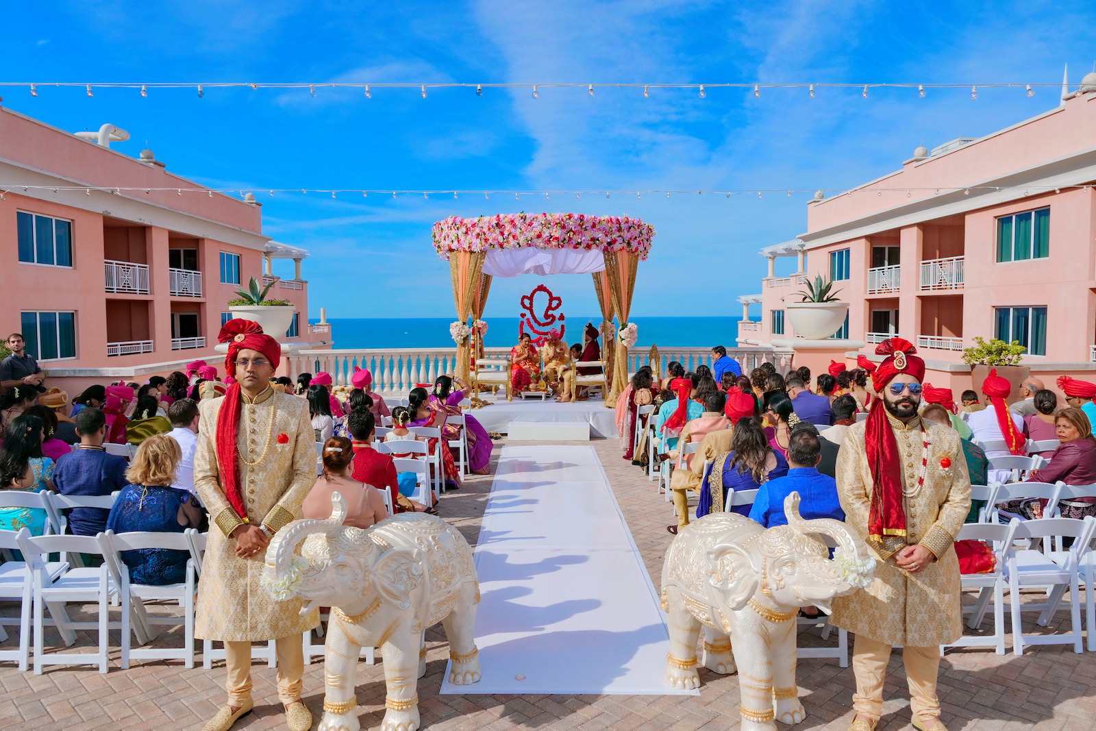 Rooftop Indian Wedding Ceremony at Clearwater Wedding Venue Hyatt Regency Clearwater Beach | Ivory and Gold Elephant Statues at Ceremony Aisle | Pink and Gold Mandap with Draping and Roses