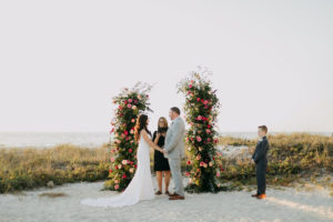 Blush Pink and Fuchsia Roses and Greenery Wedding Ceremony Backdrop Arrangements | Bride and Groom and Son at Tampa St Pete Florida COVID Destination Elopement Beach Wedding Ceremony