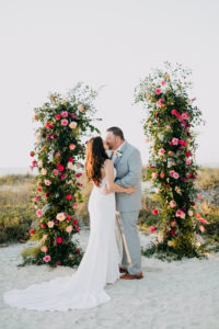 Blush Pink and Fuchsia Roses and Greenery Wedding Ceremony Backdrop Arrangements | Bride and Groom and Son at Tampa St Pete Florida COVID Destination Elopement Beach Wedding Ceremony | Amber McWhorter Photography