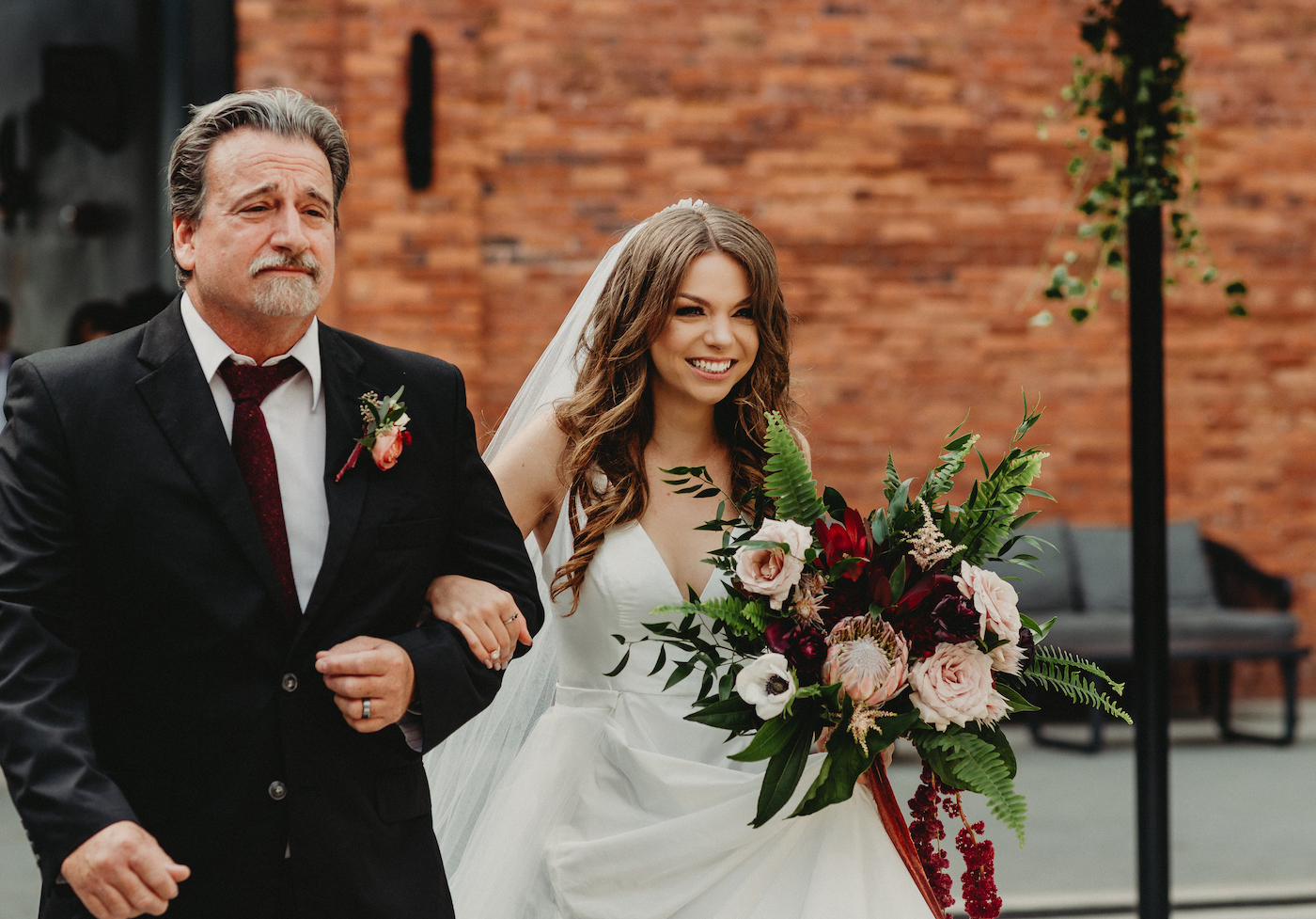 Bride Walking Down Aisle with Father during Outdoor Tampa Wedding | Wild Boho Loose Organic Greenery Bridal Bouquet with Ferns Blush Pink Roses and Protea and Red Amaranthus | Dewitt for Love Photography