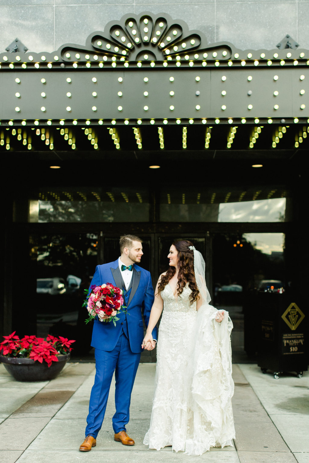 Bride and Groom Outdoor Downtown Tampa Wedding Portrait at Tampa Theater Marquis | Groom in Blue Suit with Black Satin Lapel | Rhinestone Embroidered Wedding Dress Bridal Gown | Bright Colorful Red and Pink Wedding Bridal Bouquet