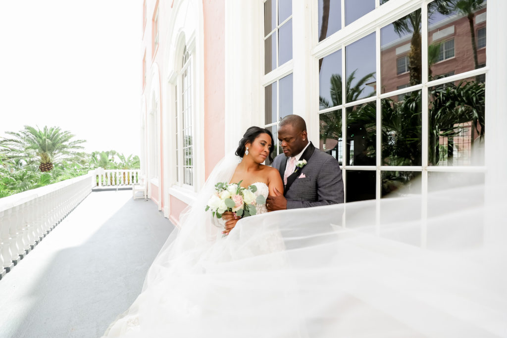Romantic Dreamy Modern St. Petersburg Bride and Groom Veil Blowing in the Wind Wedding Portrait Outside Balcony Wedding Venue Pink Palace The Don CeSar | Florida Wedding Photographer Lifelong Photography Studio | Blush Pink and Ivory Rose Bridal Bouquet by Monarch Events and Design | Wedding Dress Isabel O'Neil Bridal Shop