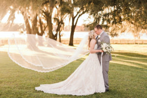 Romantic Florida Bride and Groom Kiss at Sunset with Veil Flowing in the Wind | Tampa Bay Luxury Wedding Planner and Floral Designer John Campbell Weddings