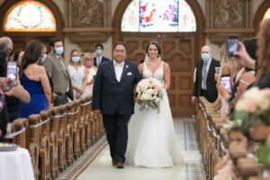 Bride Walking Down Aisle with Father during Indoor Traditional Catholic Cathedral Ceremony at Sacred Heart Church Downtown Tampa | COVID Wedding Guests Wearing Masks | V Neck Illusion Lace A Line Ballgown Wedding Dress with Rhinestone Waist Band and Cathedral Veil | Blush Pink and White Roses and Peonies Wedding Bridal Bouquet