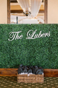 Wedding Reception Decor, Elegant Hedge Wall Greenery with Custom Bride and Groom Last Name Laser Cut Sign, Basket with Black Flip Flops for Dancing | Tampa Bay Wedding Planner Special Moments Event Planning