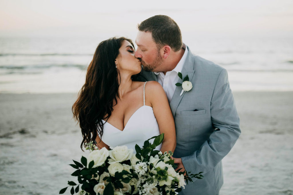 Light Blue Grey Groom Suit | Outdoor Bride and Groom Beach Portrait at Tampa St Pete Florida COVID Destination Elopement Beach Wedding Ceremony | Neutral White Ivory and Greenery Bridal Bouquet | Amber McWhorter Photography