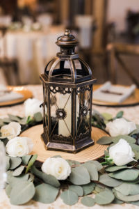 Rustic Elegant Candle Centerpieces, Antique Lantern on Wooden Stand, Surrounded by White Roses In Eucalyptus Leaf Greenery | Florida Wedding Planner and Floral Designer John Campbell Weddings | Florida Wedding Caterer Olympia Catering | Table Linens Kate Ryan Event Rentals