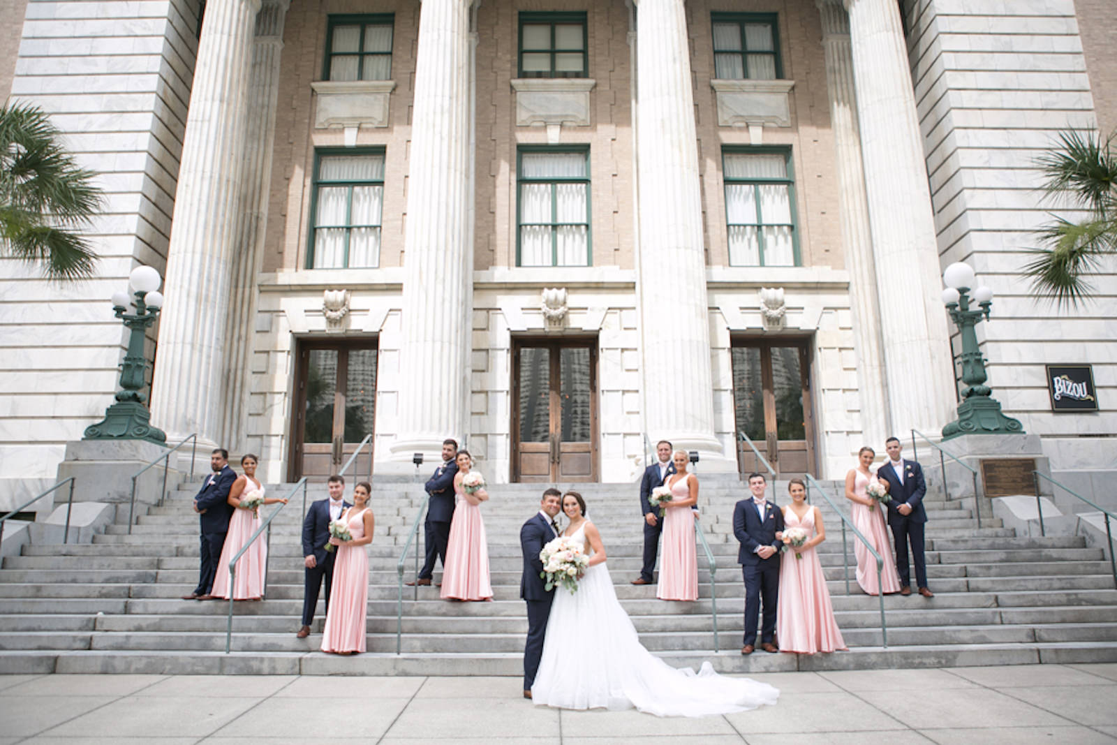 Outdoor Downtown Tampa Bride and Groom Wedding Party Portrait at Traditional Catholic Ceremony Cathedral Church Staircase | V Neck Illusion Lace A Line Ballgown Wedding Dress with Rhinestone Waist Band and Cathedral Veil | Groom and Groomsmen in Classic Navy Blue Suit with Bow Tie | Blush Pink and Ivory Roses and Peonies Bridal Bouquet with Eucalyptus Greenery | Blush Pink Long Formal Silk Satin Bridesmaid Dresses