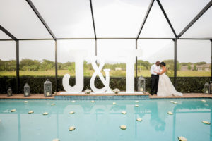Florida Bride and Groom During Intimate Wedding Reception At Private Residence, Backyard Pool Screened In with Romantic Decor and Rentals, Oversized Custom Letters | Florida Wedding Photographer Lifelong Photography Studio