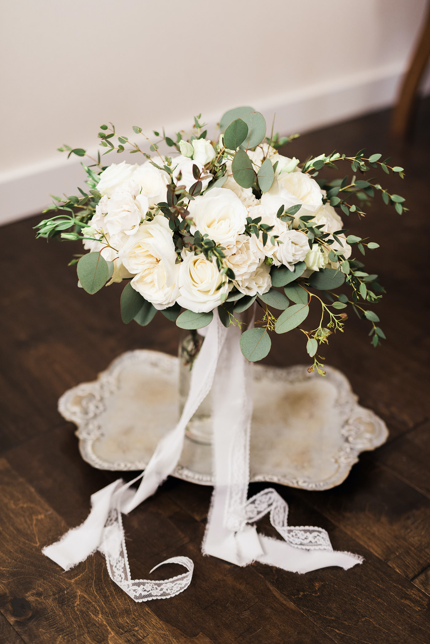 Rustic Elegant Inspired Wedding Ceremony Decor, Round Ivory Rose Bridesmaid Bouquet with Greenery and Lace Ribbon, on Antique Tray | Florida Wedding Planner and Floral Designer John Campbell Weddings