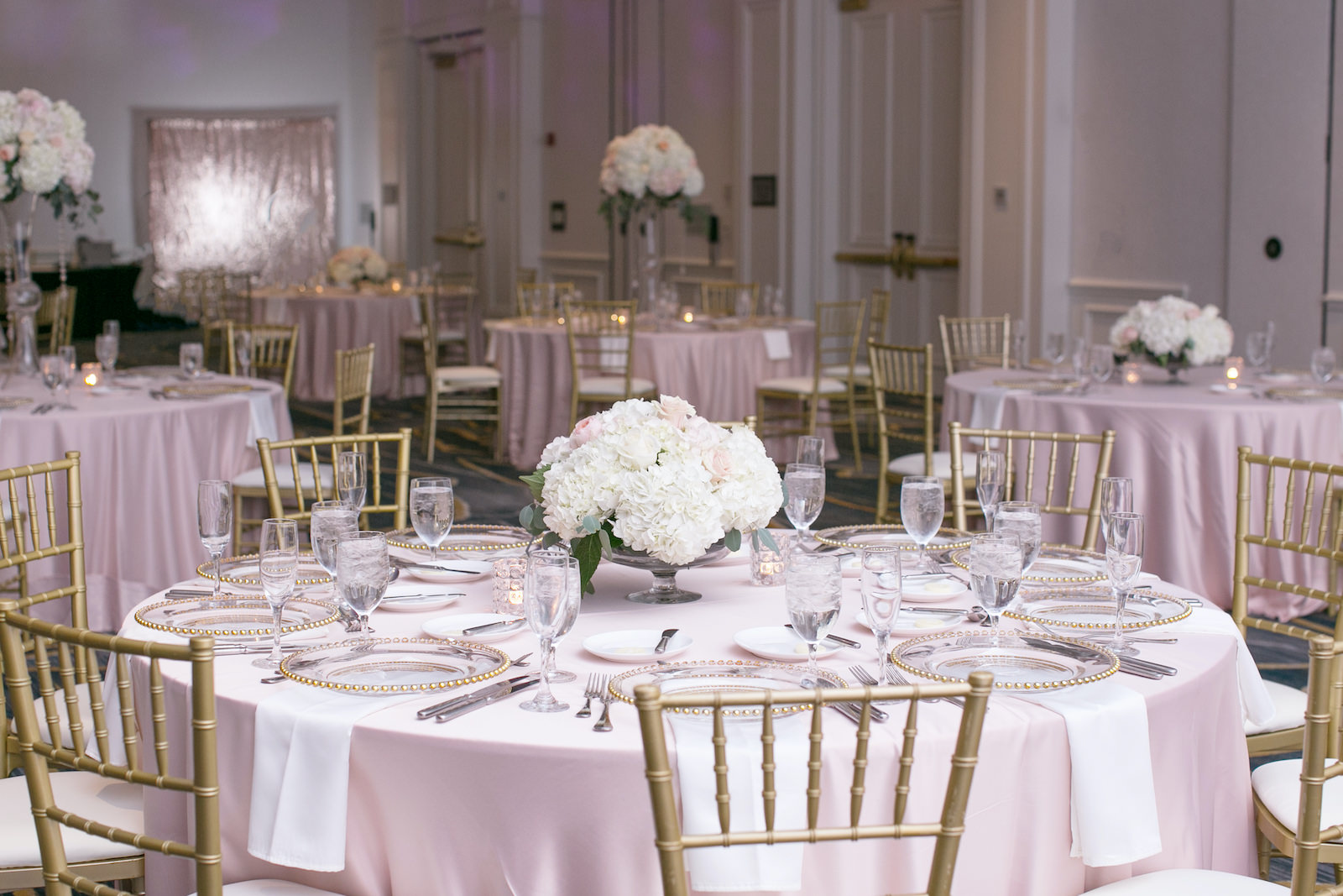 Indoor Downtown Tampa Hotel Ballroom Wedding Reception | Blush Pink Table Linens with Gold Chiavari Chairs and Gold Rim Beaded Edge Glass Chargers | Blush Pink and White Centerpieces with Roses, Hydrangea, and Eucalyptus Greenery