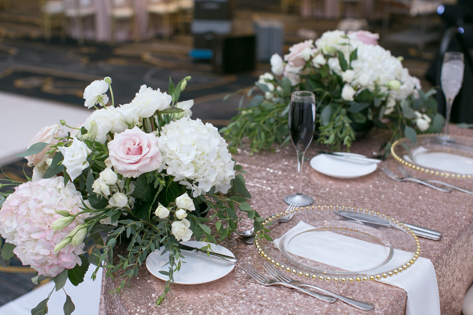 Wedding Sweetheart Table | Blush Pink Rose Gold Sequin Table Linens with Gold Chiavari Chairs and Gold Rim Beaded Edge Glass Chargers | Blush Pink and White Centerpieces with Roses, Hydrangea, and Eucalyptus Greenery