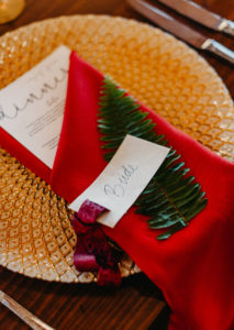 Wedding Reception Place Settings with Gold Charger Plates and Gold Flatware with Burgundy Maroon Red Napkin and Fern Greenery with Menu Card and Place Card