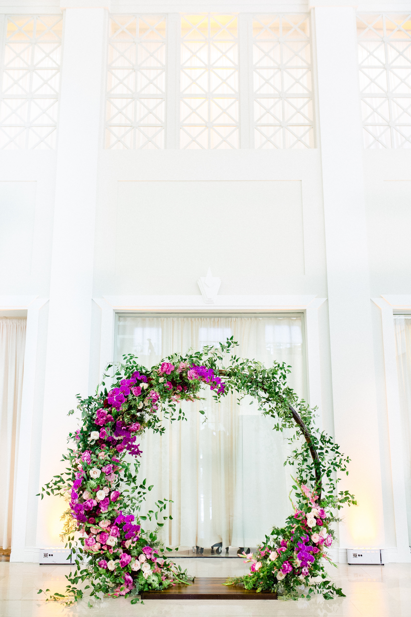 Indoor Downtown Tampa Wedding Ceremony at Tampa Wedding Venue The Vault | Bright Colorful Florida Wedding Ceremony Floral Circle Moon Round Arch with Pink Roses and Purple Orchids and Greenery