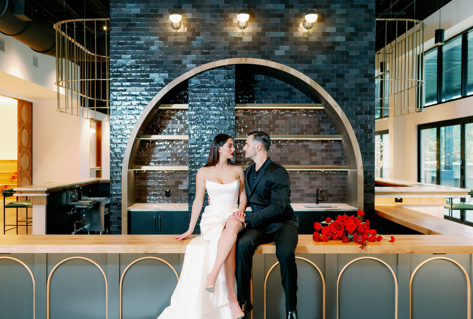 Modern Indoor South Tampa Wedding Space at Tampa Wedding Venue Hyde House | Dramatic Modern Ines di Santo High Slit Wedding Dress by Isabel Oneil Bridal | Groom in All Black Suit | Modern Dramatic Unique Asymmetrical Red Wedding Bridal Bouquet with Ranunculus Tulips Protea Roses Anemone and Amaryllis