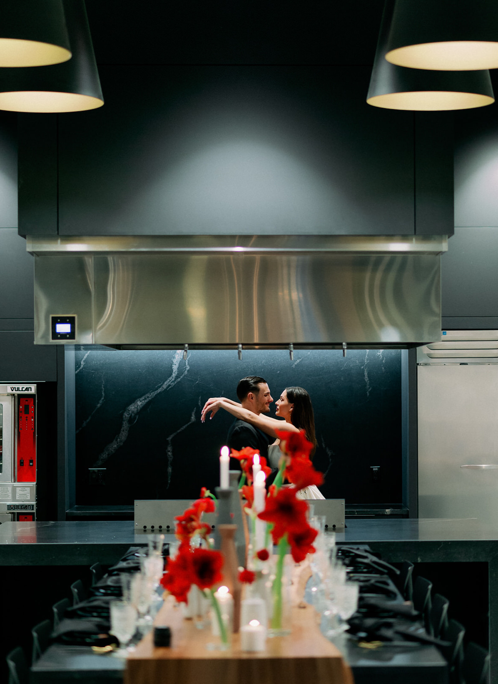 Bride and Groom Indoor Portrait at Modern Indoor South Tampa Venue Hyde House | Long Black Feasting Table with Live Edge Wood and Red Amaryllis Bud Vase Centerpieces with Candles