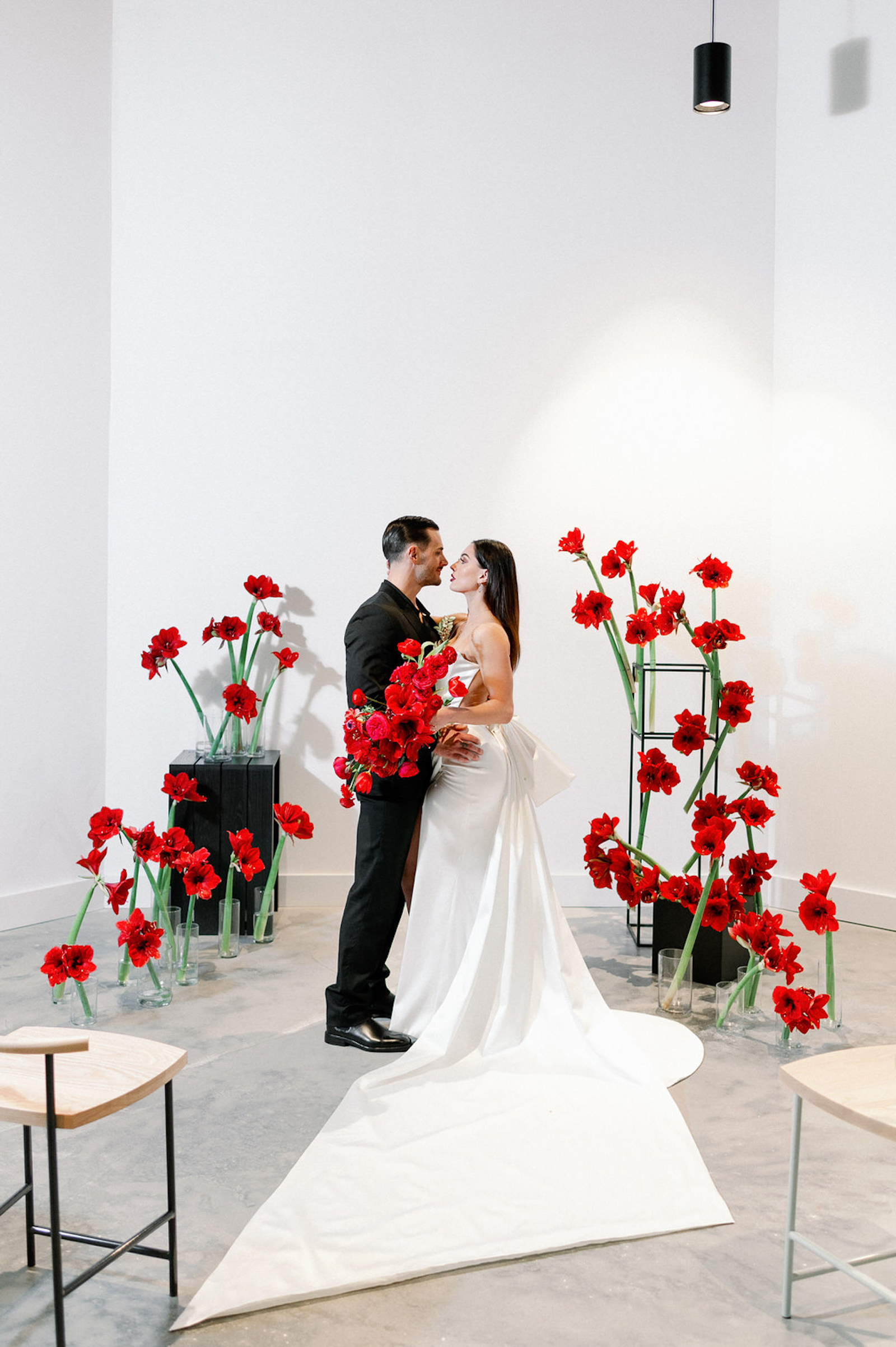 Modern Clean Indoor Ceremony Space at Tampa Wedding Venue Hyde House | Black White and Red Ceremony Backdrop with Red Amaryllis and Black Columns | Dramatic Modern Ines di Santo Wedding Dress by Isabel Oneil Bridal | Groom in All Black Suit | Modern Dramatic Unique Asymmetrical Red Wedding Bridal Bouquet with Ranunculus Tulips Protea Roses Anemone and Amaryllis