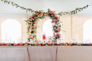 Elegant Tropical Tent Wedding Reception Decor, Lush Coral, Pink and Palm Tree Leaves Lush Floral Arch Behind Sweetheart Table, Hanging Flowers | Tampa Bay Wedding Planner NK Weddings