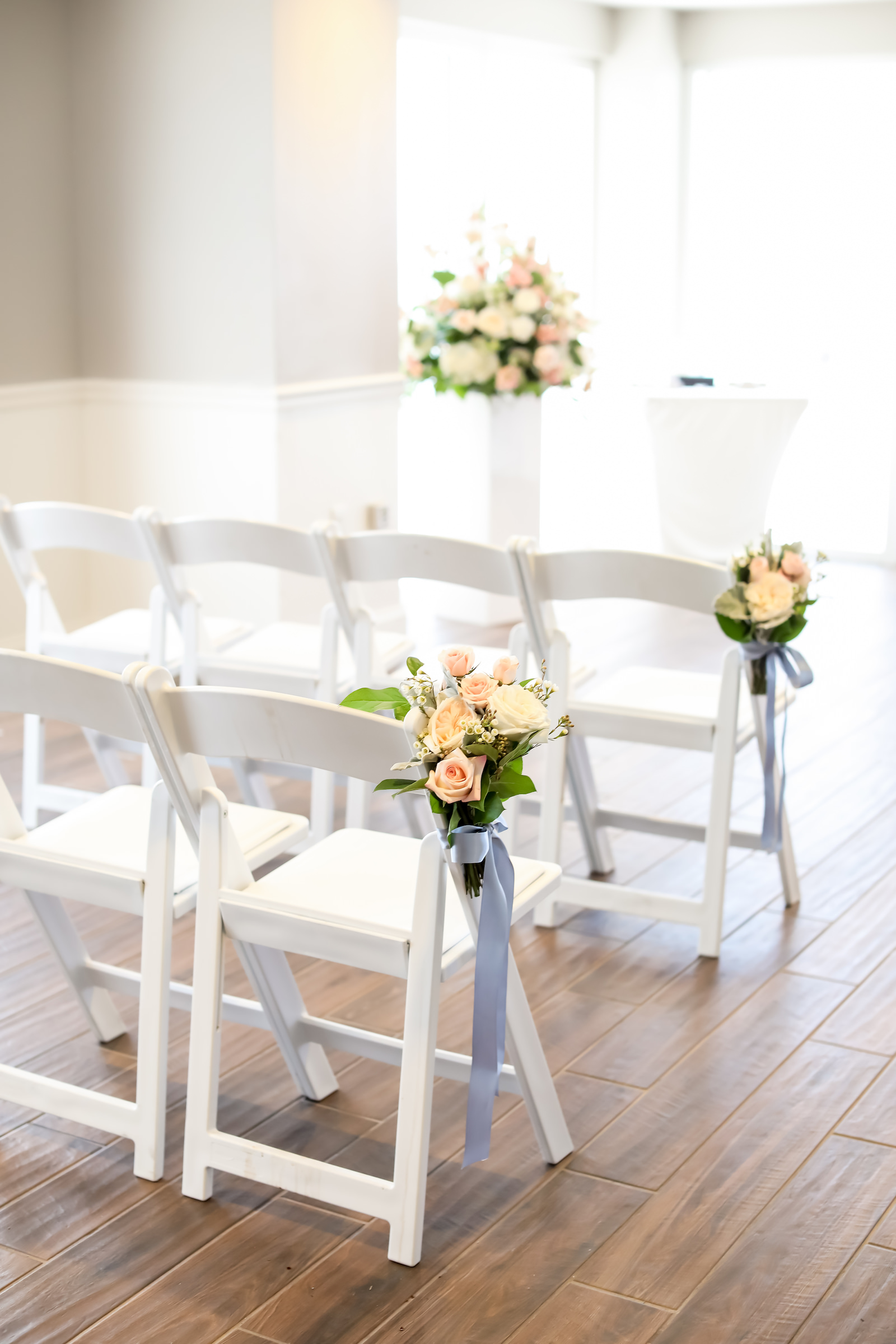 Indoor Wedding Ceremony at Clearwater Beach Venue Hyatt Regency Clearwater Beach | White Garden Chairs with Blush Pink and White Rose Floral Arrangements with Dusty Blue Grey Ribbon