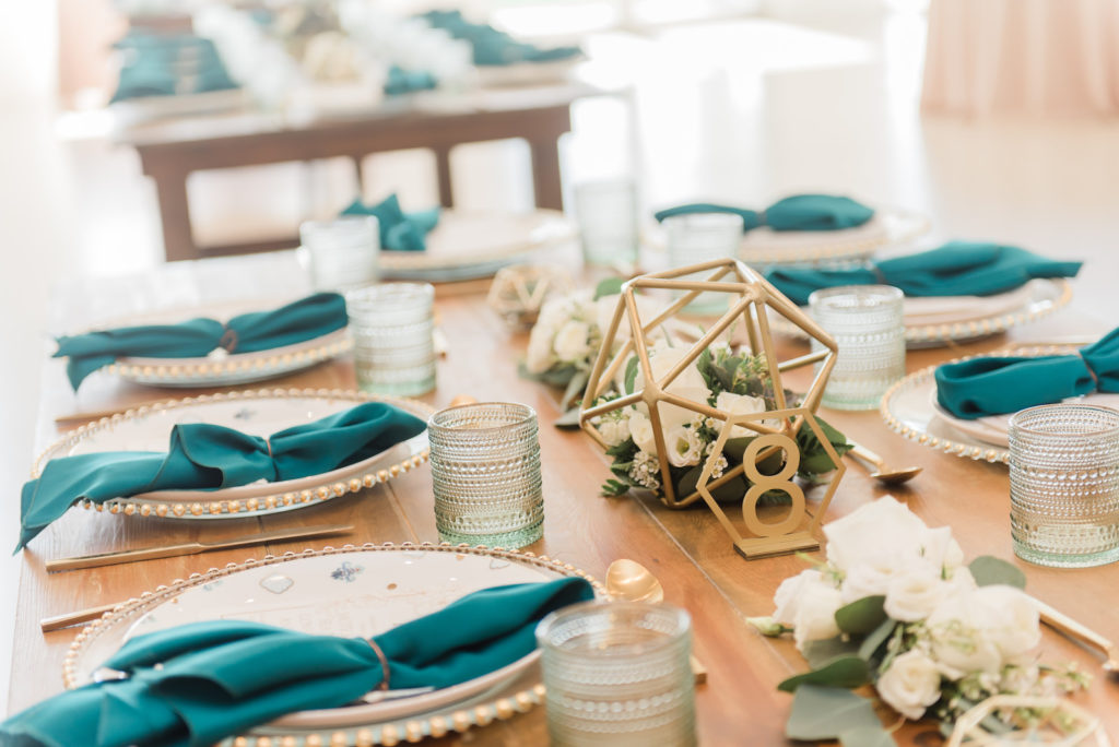 South Tampa Brunch Wedding | Rustic Wood Farm Feasting Tables | Gold Glass Beaded Edge Chargers with Fortessa Plates, Gold Flatware, Aqua Cups and Teal Turquoise Napkins | Gold Geometric Wedding Centerpieces and Table Numbers with White Roses and Eucalyptus Greenery | Winsor Event Studio