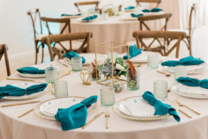South Tampa Brunch Wedding with Bacon Bouquets | Rustic Wood Farm Feasting Tables with Cross Back Chairs | Gold Glass Beaded Edge Chargers with Fortessa Plates, Gold Flatware, Aqua Cups and Teal Turquoise Napkins | Gold Geometric Lantern Centerpiece with Succulents, White Roses, and Eucalyptus Greenery | Winsor Event Studio